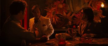 Movie still from “Casa de mi Padre” (2012), directed by Matt Piedmont – A man sitting at a table in front of flowers; Medium shot, Over the shoulder angle