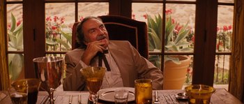 Movie still from “Casa de mi Padre” (2012), directed by Matt Piedmont – An older man sitting at a dinner table with his hand on his chin; Medium shot, Low angle