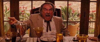 Movie still from “Casa de mi Padre” (2012), directed by Matt Piedmont – An older man sitting at a dinner table with his mouth wide open; Medium shot, Low angle