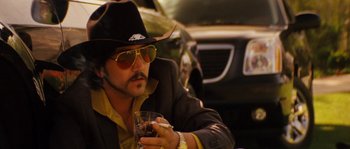 Movie still from “Casa de mi Padre” (2012), directed by Matt Piedmont – A man wearing a cowboy hat and sunglasses holding a glass of wine; Close Up shot, Low angle