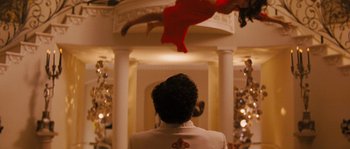 Movie still from “Casa de mi Padre” (2012), directed by Matt Piedmont – A man standing in front of a pillar with a red dress hanging from the ceiling; Wide shot, Overhead angle