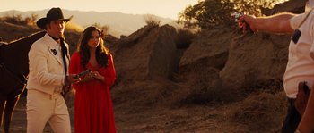 Movie still from “Casa de mi Padre” (2012), directed by Matt Piedmont – A woman in a red dress standing on a dirt field; Medium shot, Over the shoulder angle