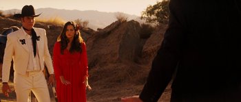 Movie still from “Casa de mi Padre” (2012), directed by Matt Piedmont – A woman in a red dress standing next to a man in a black suit; Medium shot, Over the shoulder angle