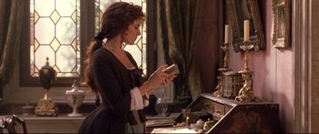 Movie still from “Casanova” (2005), directed by Lasse Hallström – A woman holding a cell phone while standing in front of a mirror; Medium shot, Over the shoulder angle