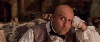 Movie still from “Casanova” (2005), directed by Lasse Hallström – A man with a bald head wearing a vest and a bow tie; Close Up shot, Low angle