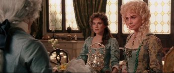 Movie still from “Casanova” (2005), directed by Lasse Hallström – A woman sitting at a dining table with a vase of fruit; Medium shot, Over the shoulder angle