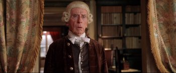 Movie still from “Casanova” (2005), directed by Lasse Hallström – An older man in a wig and wig stands in front of a bookshelf; Close Up shot, Low angle