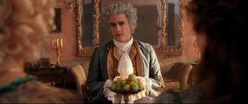 Movie still from “Casanova” (2005), directed by Lasse Hallström – A man in a wig holding a bowl of fruit; Medium shot, Over the shoulder angle