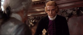 Movie still from “Casanova” (2005), directed by Lasse Hallström – A man in a wig standing in front of a wooden wall; Medium shot, Over the shoulder angle