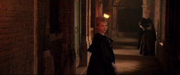 Movie still from “Casanova” (2005), directed by Lasse Hallström – A woman in a black coat standing in a dark alley; Medium shot, Over the shoulder angle