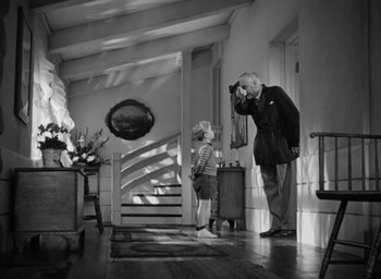 Movie still from “Casanova Brown” (1944), directed by Sam Wood – An older man and a young boy are standing in a room; Wide shot, Low angle