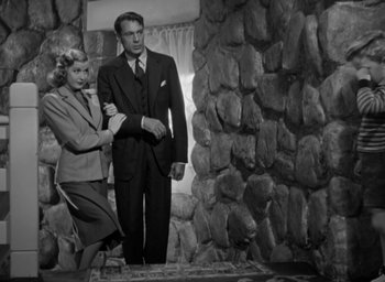 Movie still from “Casanova Brown” (1944), directed by Sam Wood – A man and a woman standing next to each other in front of a stone wall; Medium shot, Low angle
