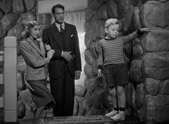 Movie still from “Casanova Brown” (1944), directed by Sam Wood – A man and a woman and a boy standing in front of a stone wall; Medium shot, Low angle