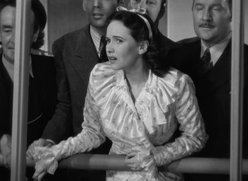 Movie still from “Casanova Brown” (1944), directed by Sam Wood – An old photo of a woman sitting in front of a group of men; Medium shot, Low angle