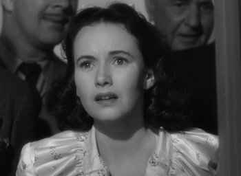 Movie still from “Casanova Brown” (1944), directed by Sam Wood – An old photo of a woman looking sad in front of two men; Close Up shot, High angle