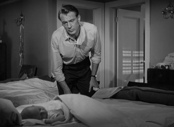 Movie still from “Casanova Brown” (1944), directed by Sam Wood – A black and white photo of a man standing over a bed; Medium shot, High angle