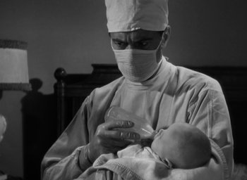 Movie still from “Casanova Brown” (1944), directed by Sam Wood – A doctor holding a baby while wearing a surgical mask; Close Up shot, Low angle