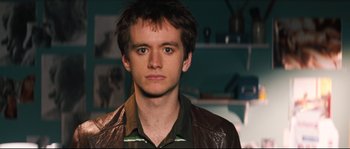 A young man wearing a leather jacket and looking at the camera