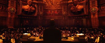 Movie still from “Casshern” (2004), directed by Kazuaki Kiriya – A man sitting in front of an audience in a theater; Extreme Wide shot, Low angle