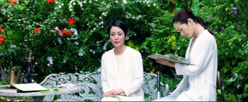 Movie still from “Casshern” (2004), directed by Kazuaki Kiriya – A woman sitting on top of a bench next to another woman; Medium shot, Over the shoulder angle