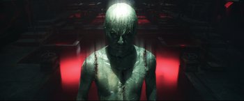 Movie still from “Casshern” (2004), directed by Kazuaki Kiriya – A man with green body paint and red lights in the background; Medium shot, High angle
