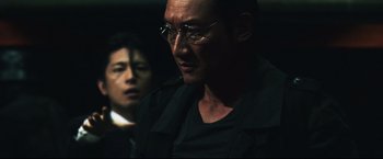 Movie still from “Casshern” (2004), directed by Kazuaki Kiriya – A person wearing glasses and a black shirt; Close Up shot, Over the shoulder angle