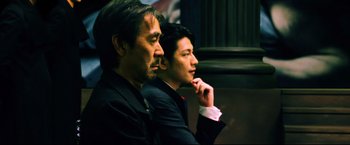 Movie still from “Casshern” (2004), directed by Kazuaki Kiriya – Two men in suits sitting next to each other; Close Up shot, Low angle