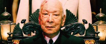 Movie still from “Casshern” (2004), directed by Kazuaki Kiriya – An old man with a black mask and some blood on his face; Close Up shot, Overhead angle