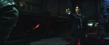 Movie still from “Casshern” (2004), directed by Kazuaki Kiriya – A man holding a cell phone in a dark room; Medium shot, Low angle