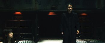 Movie still from “Casshern” (2004), directed by Kazuaki Kiriya – A man standing in the dark in front of an open door; Medium shot, Low angle