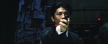 Movie still from “Casshern” (2004), directed by Kazuaki Kiriya – A man in a suit and tie holding a gun; Close Up shot, Low angle