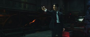 Movie still from “Casshern” (2004), directed by Kazuaki Kiriya – A man in a suit and tie holding a cell phone in his hand; Medium shot, Low angle