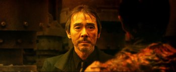 Movie still from “Casshern” (2004), directed by Kazuaki Kiriya – A person wearing a suit and tie; Close Up shot, Over the shoulder angle