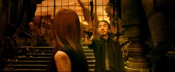 Movie still from “Casshern” (2004), directed by Kazuaki Kiriya – A man holding a gun in front of a woman in front of a mirror; Medium shot, Over the shoulder angle