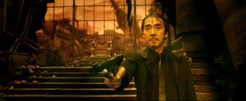 Movie still from “Casshern” (2004), directed by Kazuaki Kiriya – A man holding a gun while standing in front of a painting; Medium shot, Low angle