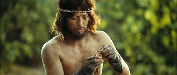 A man with long hair and a beard is holding a snake