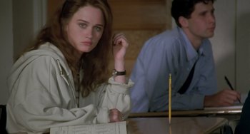 Movie still from “The Craft” (1996), directed by Andrew Fleming – A woman sitting at a table with a pencil in front of her; Medium shot, High angle