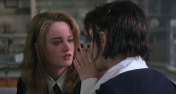 Movie still from “The Craft” (1996), directed by Andrew Fleming – A woman whispering into a woman's ear in front of another woman; Close Up shot, Over the shoulder angle