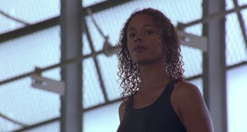 Movie still from “The Craft” (1996), directed by Andrew Fleming – A woman with long curly hair standing in front of a building; Close Up shot, Low angle