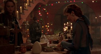 Movie still from “The Craft” (1996), directed by Andrew Fleming – A woman sitting at a table in front of candles; Medium shot, Over the shoulder angle