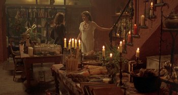 Movie still from “The Craft” (1996), directed by Andrew Fleming – A woman standing in front of candles on a table; Wide shot, High angle