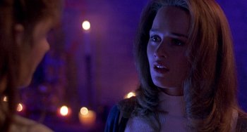 Movie still from “The Craft” (1996), directed by Andrew Fleming – A woman with long blonde hair standing in front of candles; Close Up shot, Over the shoulder angle