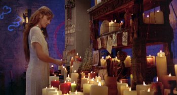 Movie still from “The Craft” (1996), directed by Andrew Fleming – A woman standing in front of candles in a room; Wide shot, High angle