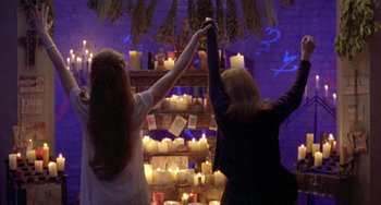 Movie still from “The Craft” (1996), directed by Andrew Fleming – Two women standing in front of a wall of lit candles; Medium shot, Low angle