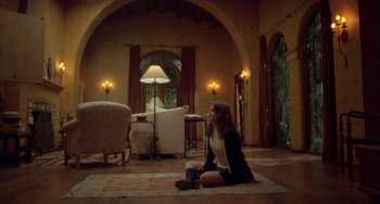 Movie still from “The Craft” (1996), directed by Andrew Fleming – A woman sitting on the ground in a living room; Wide shot, High angle