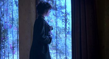 Movie still from “The Craft” (1996), directed by Andrew Fleming – A woman standing in front of a window looking outside; Wide shot, Over the shoulder angle