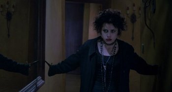 Movie still from “The Craft” (1996), directed by Andrew Fleming – A woman in a black jacket holding a knife in her hand; Medium shot, Over the shoulder angle