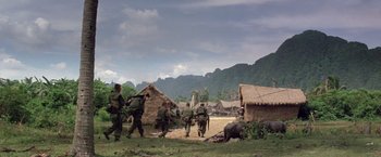 Movie still from “Casualties of War” (1989), directed by Brian De Palma – A group of men walking across a dirt field; Extreme Wide shot, Low angle