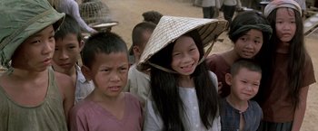 Movie still from “Casualties of War” (1989), directed by Brian De Palma – Two young children wearing hats and smiling for the camera; Close Up shot, High angle