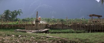 Movie still from “Casualties of War” (1989), directed by Brian De Palma – A wooden fence in the middle of a green field; Extreme Wide shot, Low angle